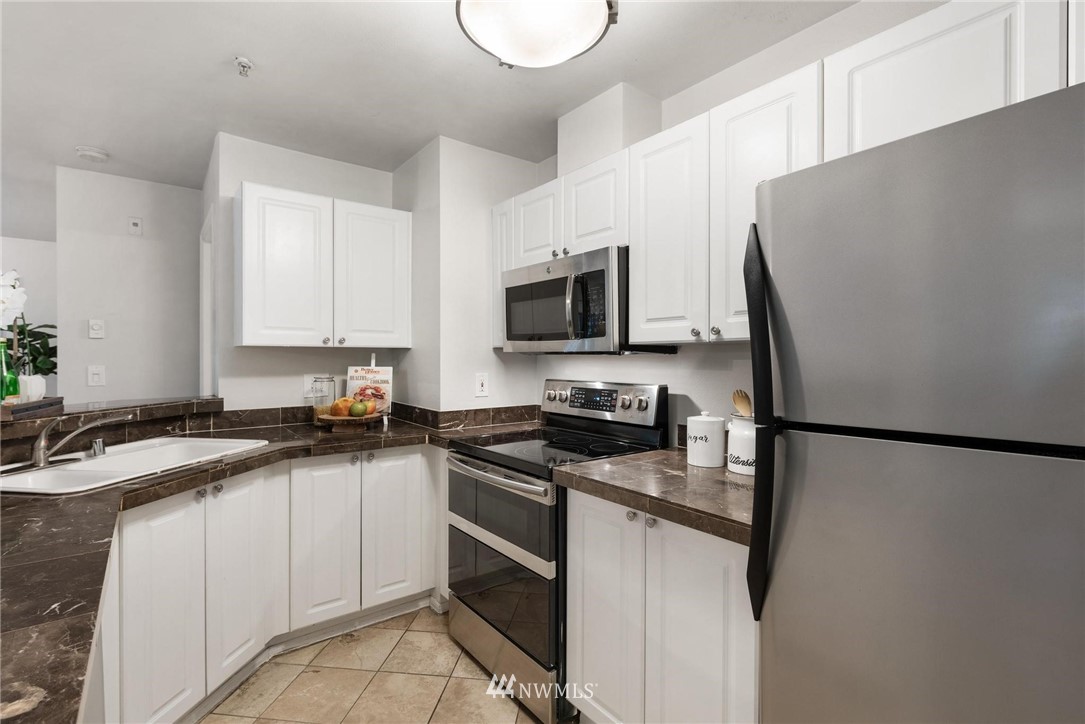 18505 Southeast Newport Way, Unit E320 Issaquah, WA 98027 - Photo 7 of 18 a kitchen with a sink a refrigerator a stove a microwave and cabinets