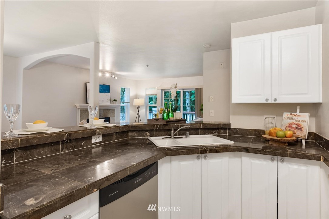18505 Southeast Newport Way, Unit E320 Issaquah, WA 98027 - Photo 8 of 18 a kitchen with stainless steel appliances granite countertop a sink a stove and white cabinets