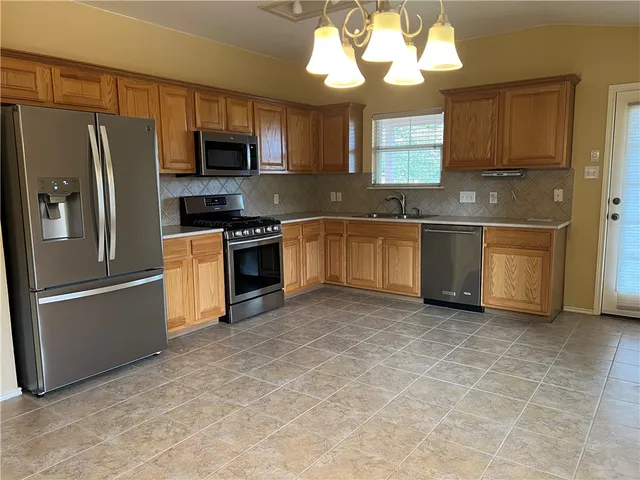 a kitchen with stainless steel appliances granite countertop a stove a sink dishwasher a refrigerator and a microwave oven