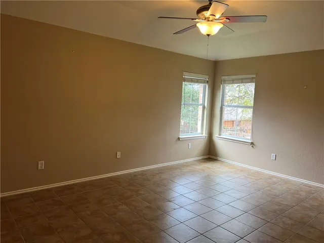 an empty room with windows and chandelier fan