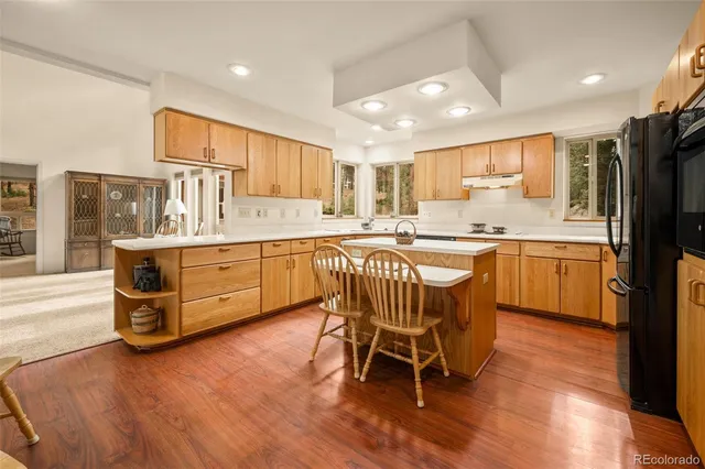 a kitchen with stainless steel appliances a sink a stove a refrigerator cabinets and wooden floor