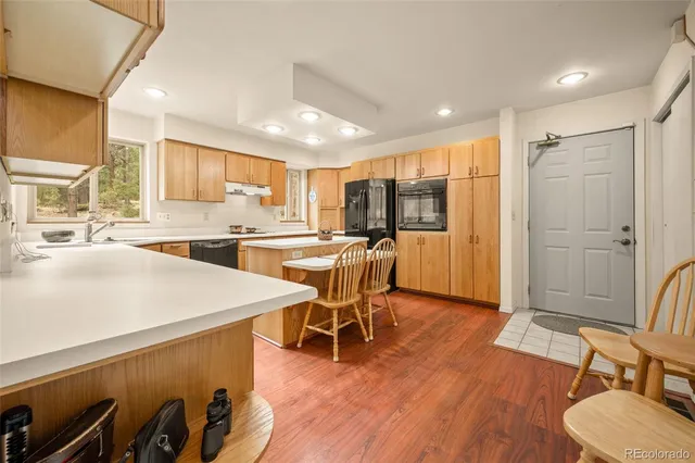 a kitchen with stainless steel appliances a dining table chairs stove refrigerator and cabinets