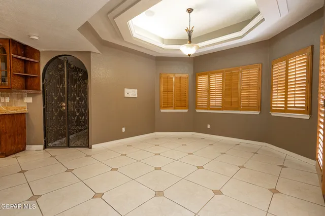 a view of an empty room with chandelier fan and wooden floor