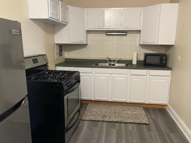 a white kitchen with granite countertop stainless steel appliances