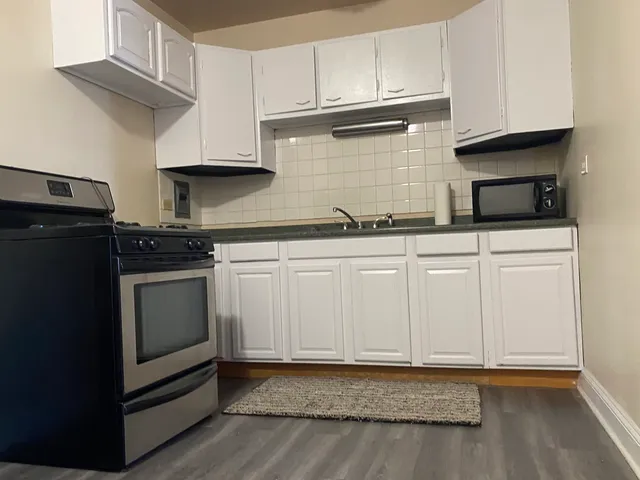 a kitchen with granite countertop white cabinets and stainless steel appliances