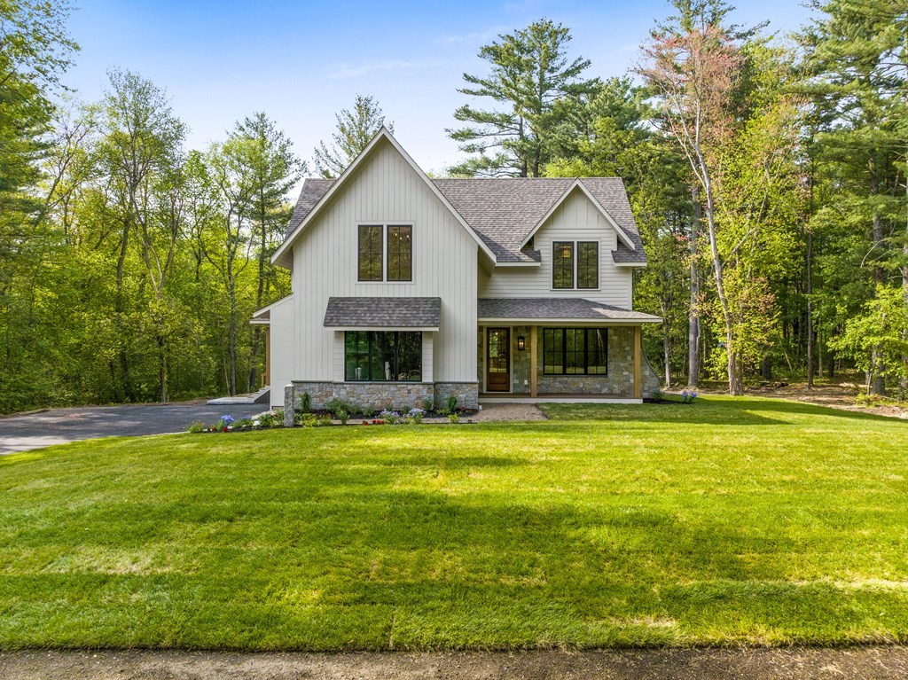 a front view of house with yard and trees in the background