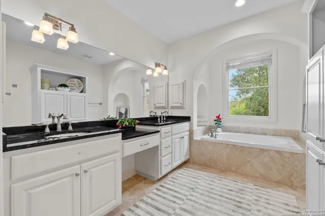 a kitchen with granite countertop a sink dishwasher a stove and white cabinets with wooden floor