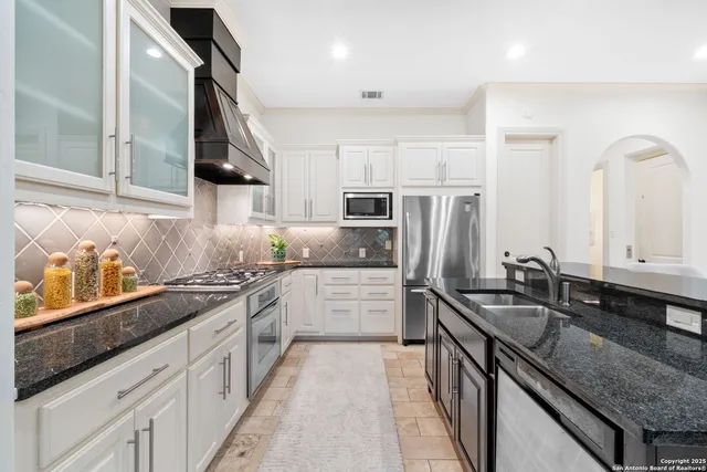 a kitchen with granite countertop stainless steel appliances a sink stove top oven and cabinets