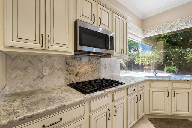 a kitchen with stainless steel appliances granite countertop white cabinets and a stove