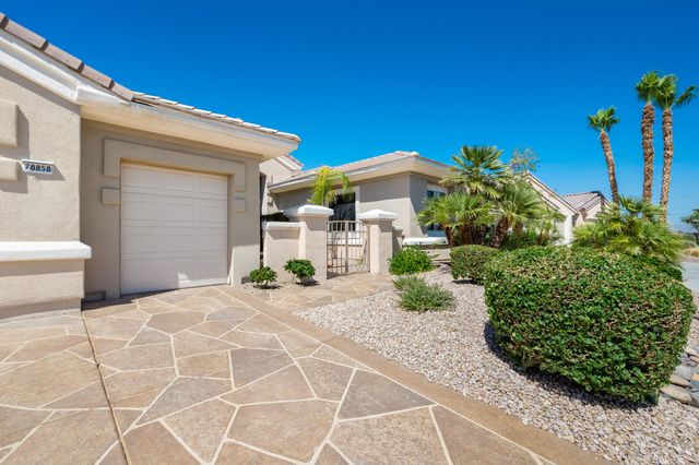 a view of a white house with large windows and a small yard