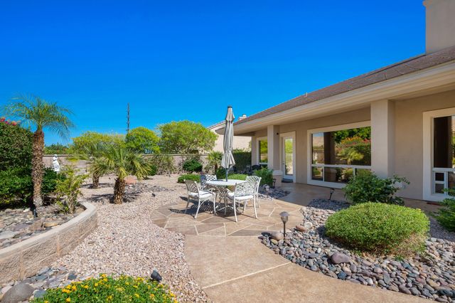 a view of a patio with couches table and chairs under an umbrella with palm trees