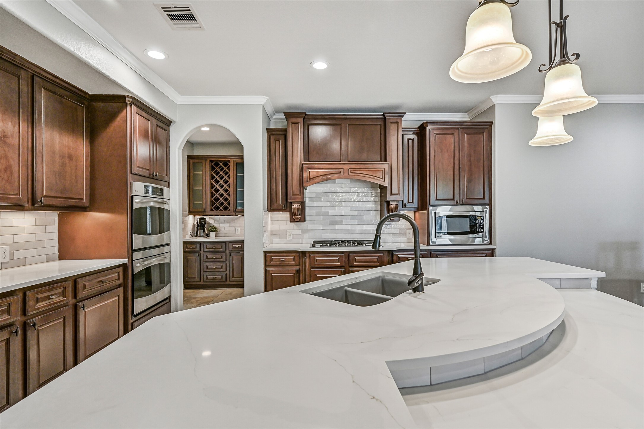 1008 Point Isabel Lane Friendswood, TX 77546 - Photo 14 of 50 The oversized island offers extensive prep space, an undermount sink with gooseneck faucet, and seating along one side. Clean quartz surfaces and open sightlines make this a functional centerpiece for daily living.