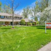 a view of a house with a big yard and large trees