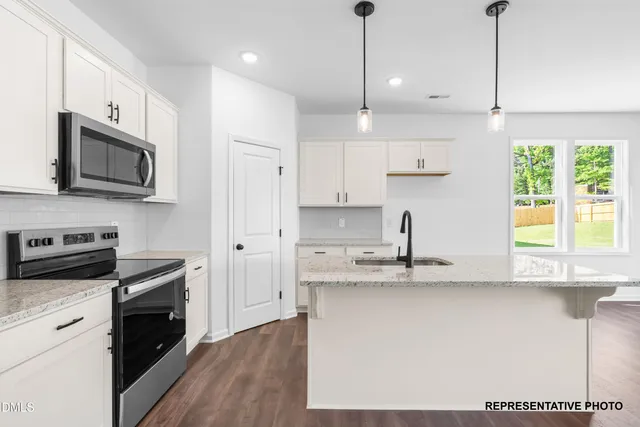 a kitchen with stainless steel appliances granite countertop a sink a stove a refrigerator and island with wooden floor