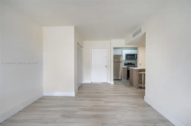 a view of a kitchen with a stove wooden cabinets and entryway