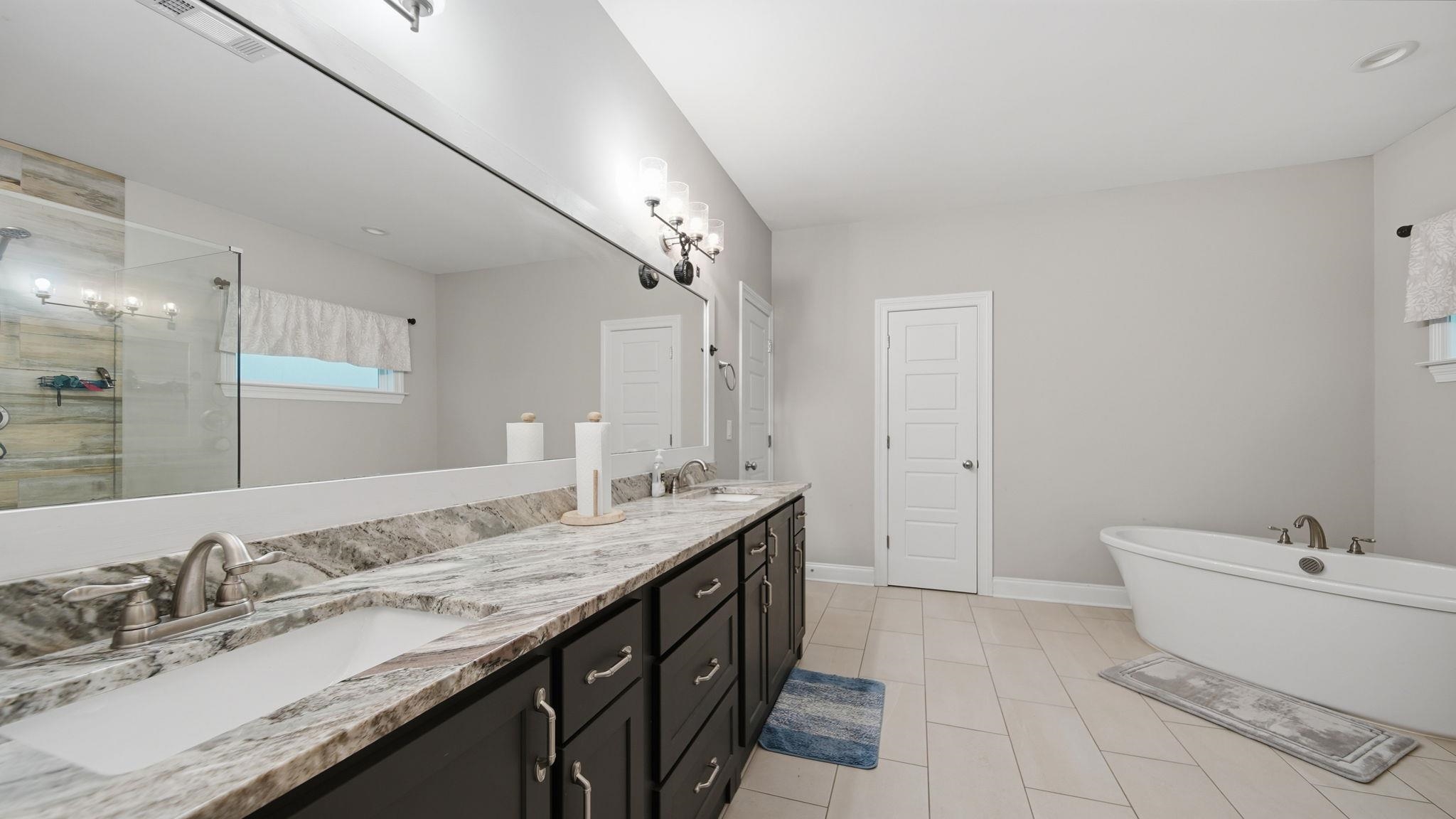 70 Trinity Cove Atoka, TN 38004 - Photo 10 of 25 Spacious bathroom featuring a double vanity with stone countertops, undermount sinks, and dark wood cabinetry
