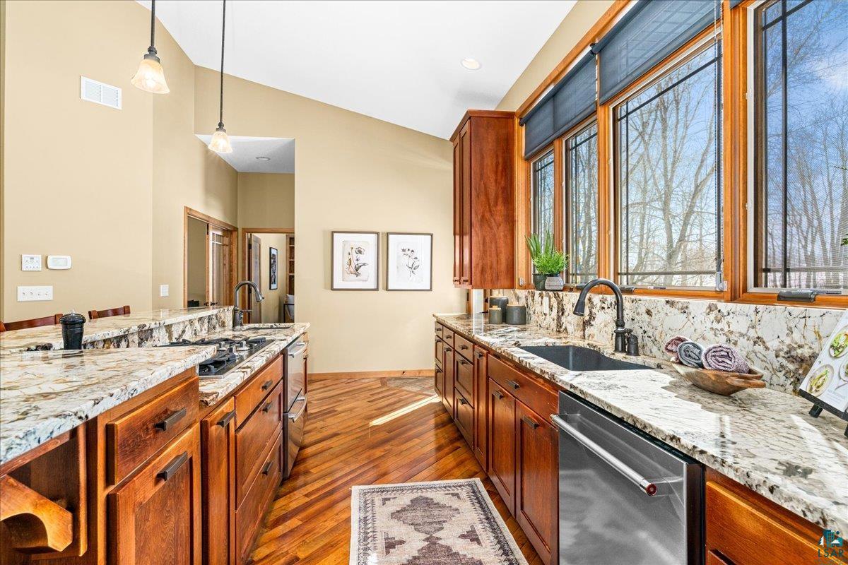 92598 Spells Road Sturgeon Lake, MN 55783 - Photo 13 of 60 Kitchen featuring light stone counters, stainless steel appliances, vaulted ceiling, hanging light fixtures, and dark wood-style floors