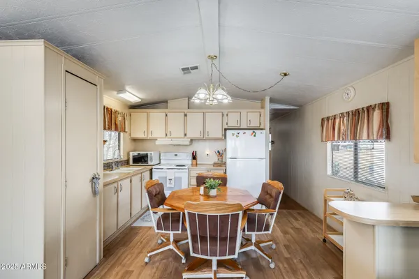 a white kitchen with a refrigerator a stove a dining table and chairs