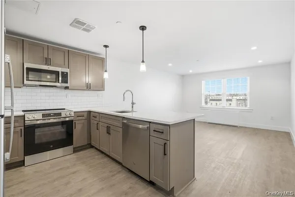 a kitchen with stainless steel appliances granite countertop a sink a stove a microwave and wooden floor