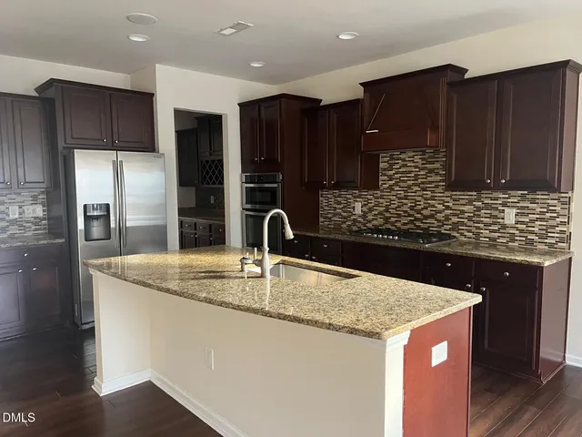 a kitchen with kitchen island granite countertop a sink and a refrigerator