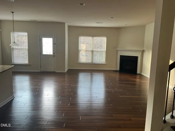 an empty room with wooden floor fireplace and windows