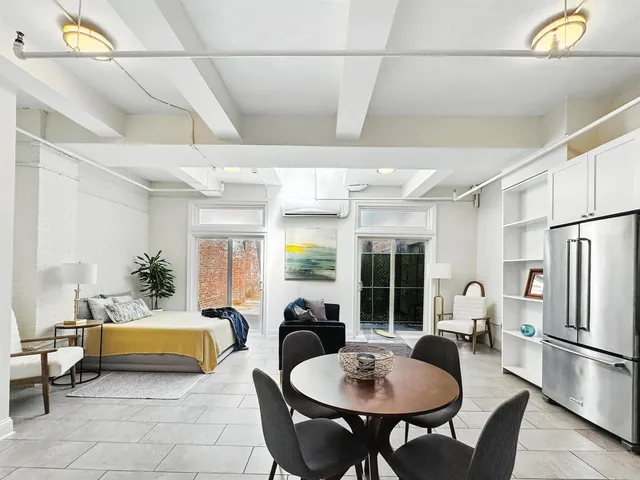 a living room with stainless steel appliances furniture dining table and a refrigerator