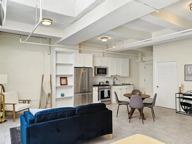 a living room with stainless steel appliances kitchen island granite countertop furniture and a refrigerator