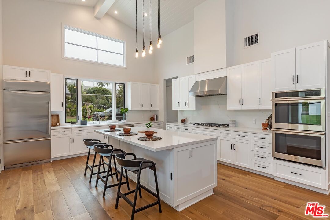 5916 Bonsall Drive Malibu, CA 90265 - Photo 7 of 20 a kitchen with stainless steel appliances a stove a sink dishwasher a refrigerator and a dining table with wooden floor