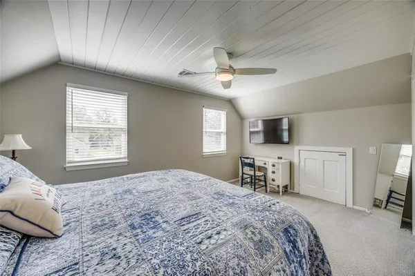 a bedroom with a large bed a flat tv screen and a dresser