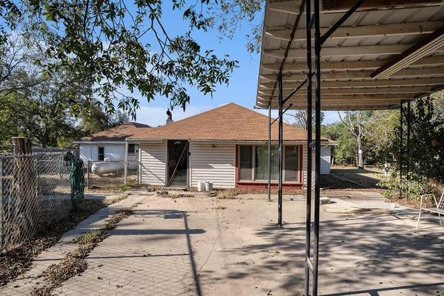 a patio with a table and chairs and potted plants