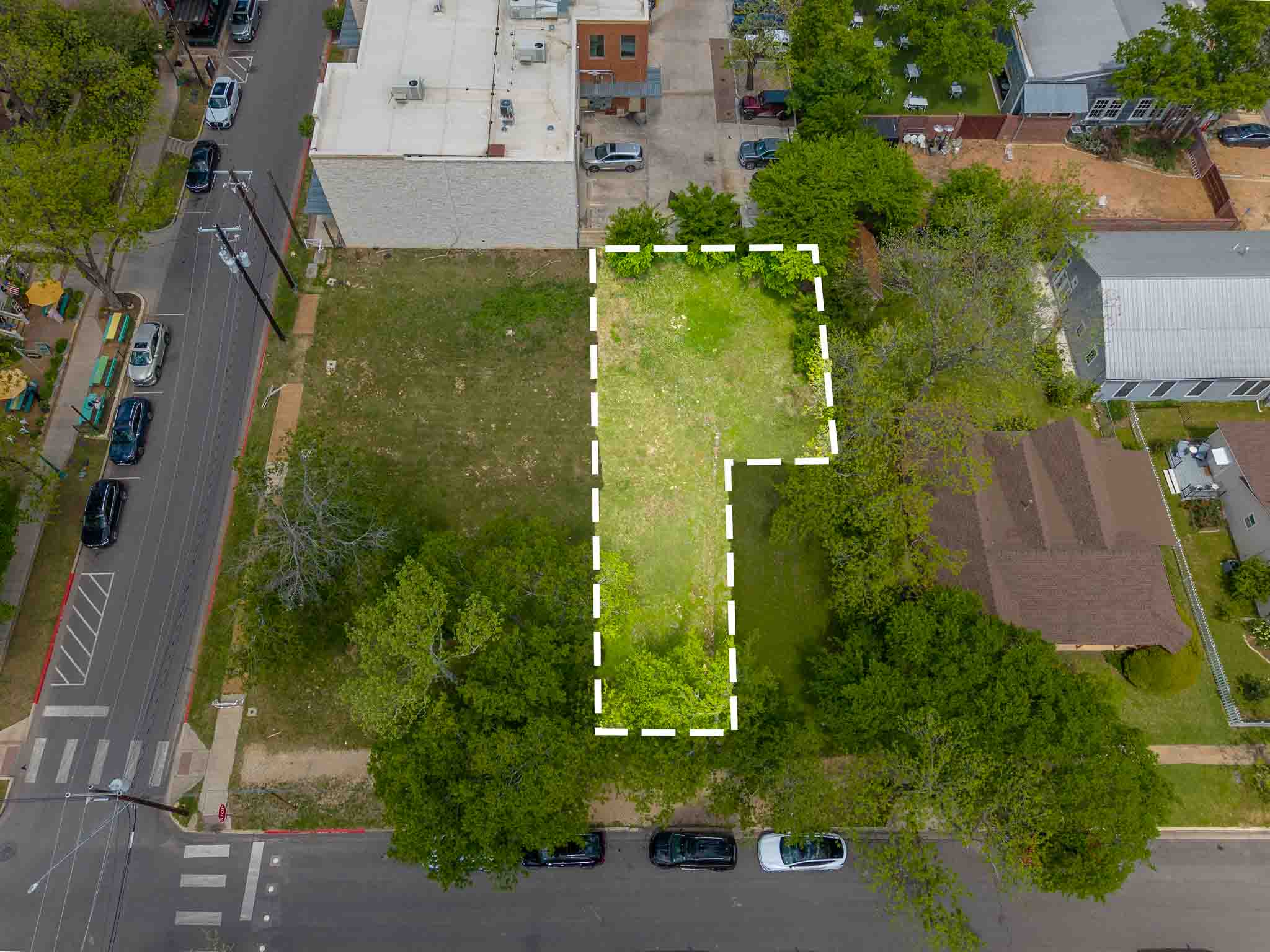 Expansive land parcel featuring existing tree coverage and frontage on a paved street
