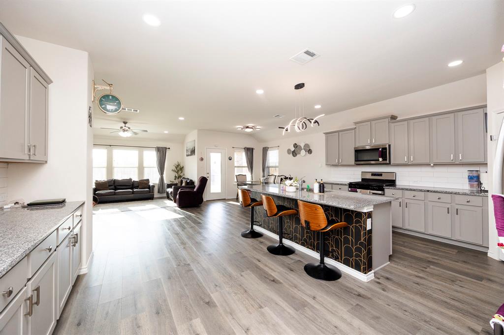 3229 Trails End Road Aubrey, TX 76227 - Photo 25 of 25 Kitchen with tasteful backsplash, gray cabinetry, open floor plan, a breakfast bar area, and recessed lighting