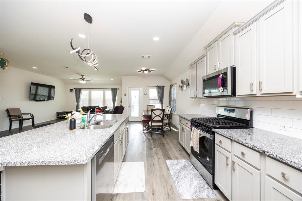 3229 Trails End Road Aubrey, TX 76227 - Photo 23 of 25 Kitchen with appliances with stainless steel finishes, open floor plan, light stone countertops, decorative backsplash, and decorative light fixtures
