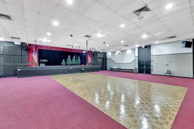 a view of an empty room with kitchen and a window