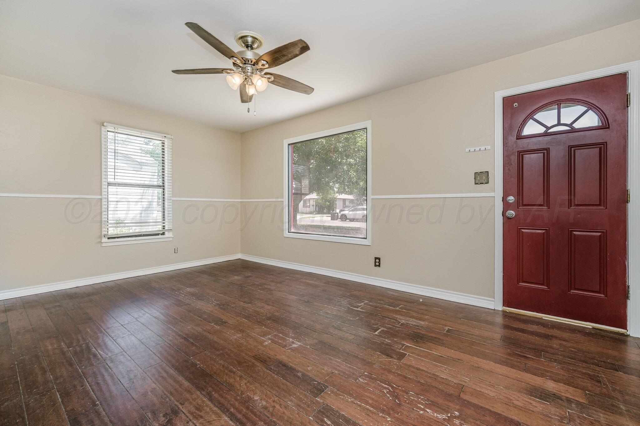 4004 South Van Buren Street Amarillo, TX 79110 - Photo 2 of 17 an empty room with wooden floor ceiling fan and windows