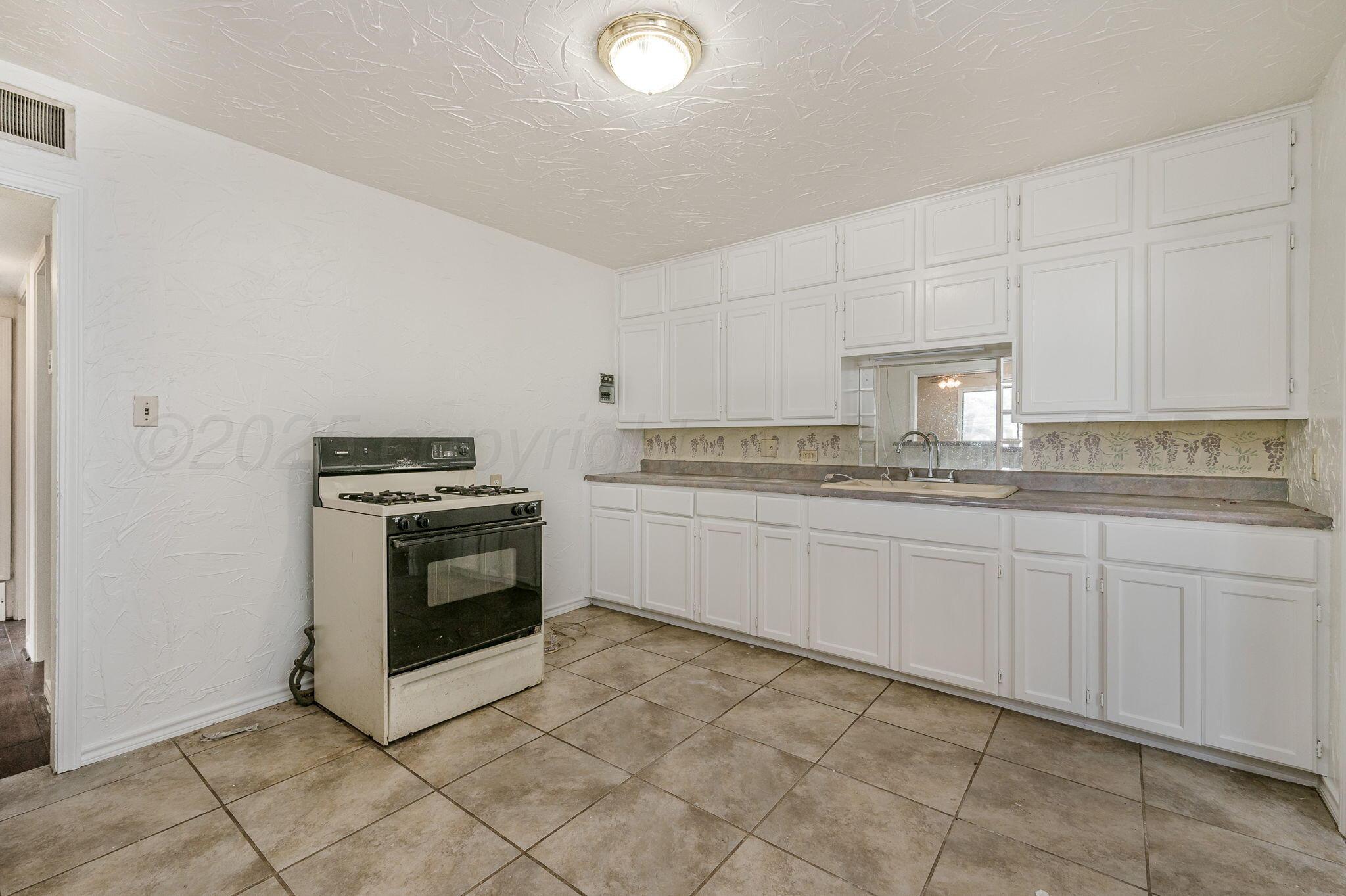 4004 South Van Buren Street Amarillo, TX 79110 - Photo 6 of 17 a kitchen with cabinets and white appliances