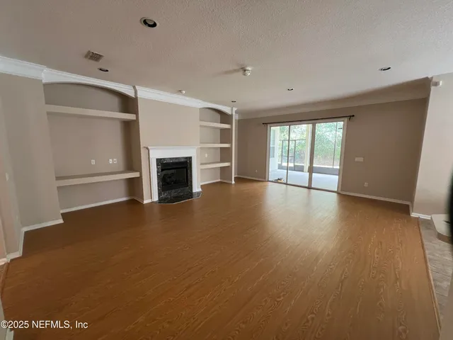 an empty room with wooden floor fireplace and windows