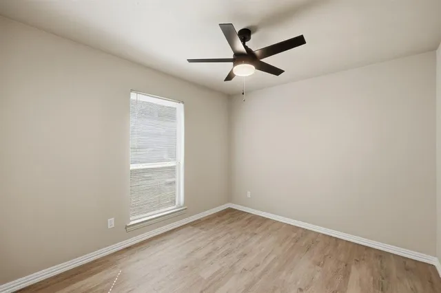 an empty room with a window and a fan