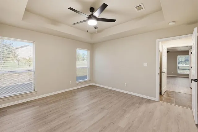 an empty room with wooden floor fan and windows