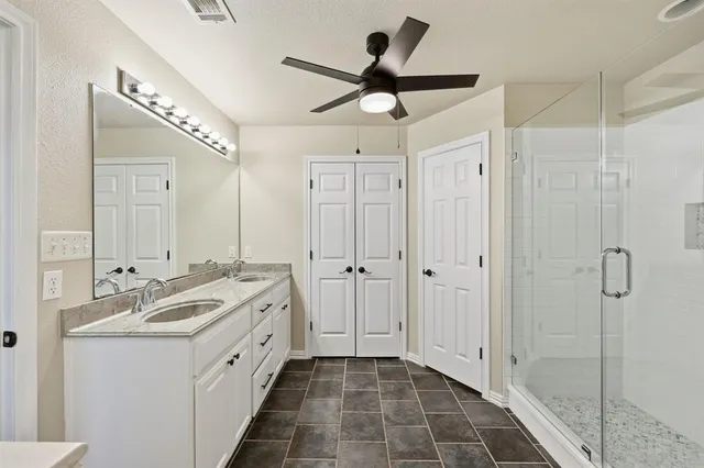 a spacious bathroom with a double vanity sink a mirror and shower