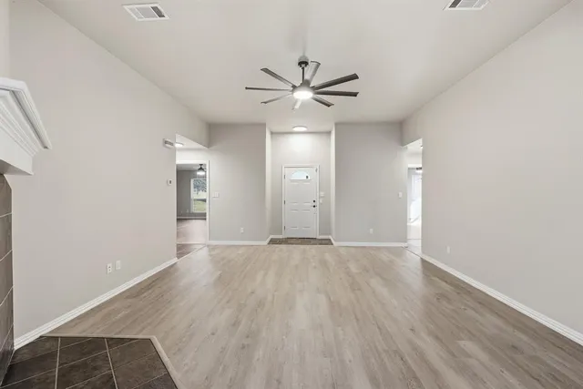 an empty room with wooden floor and a ceiling fan