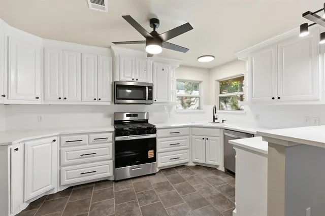 a kitchen with cabinets stainless steel appliances and a window