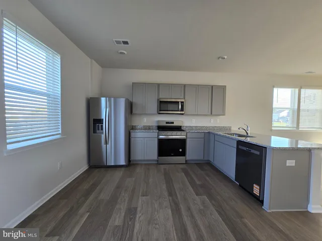a kitchen with stainless steel appliances wooden floors and wooden cabinets