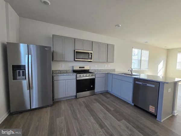 a kitchen with granite countertop wooden floors stainless steel appliances and a window