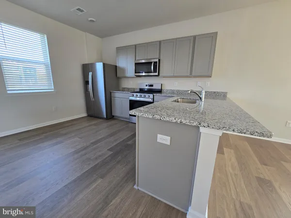 a kitchen with granite countertop a refrigerator a stove a sink and dishwasher with wooden floors