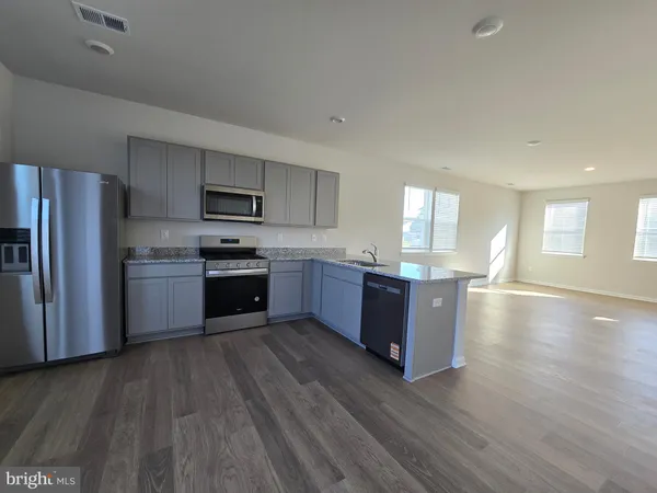 a kitchen with stainless steel appliances granite countertop a refrigerator a stove top oven a sink dishwasher and wooden floor