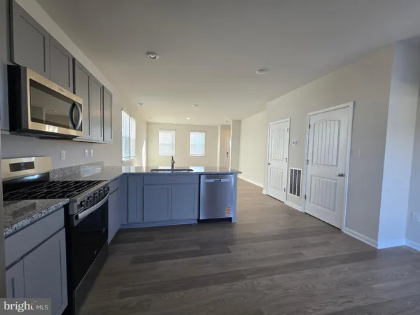 a large kitchen with stainless steel appliances granite countertop a stove a sink dishwasher and a microwave oven with wooden floor