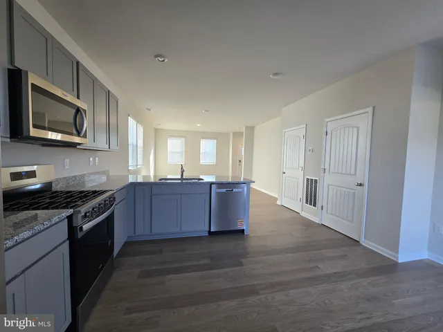 a large kitchen with stainless steel appliances granite countertop a stove a sink dishwasher and a microwave oven with wooden floor