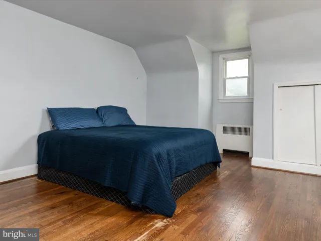 a bedroom with a bed window and wooden floor