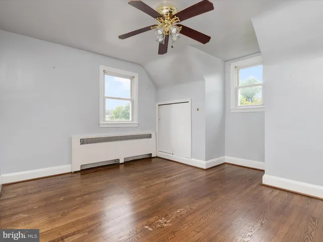 an empty room with wooden floor chandelier fan and windows